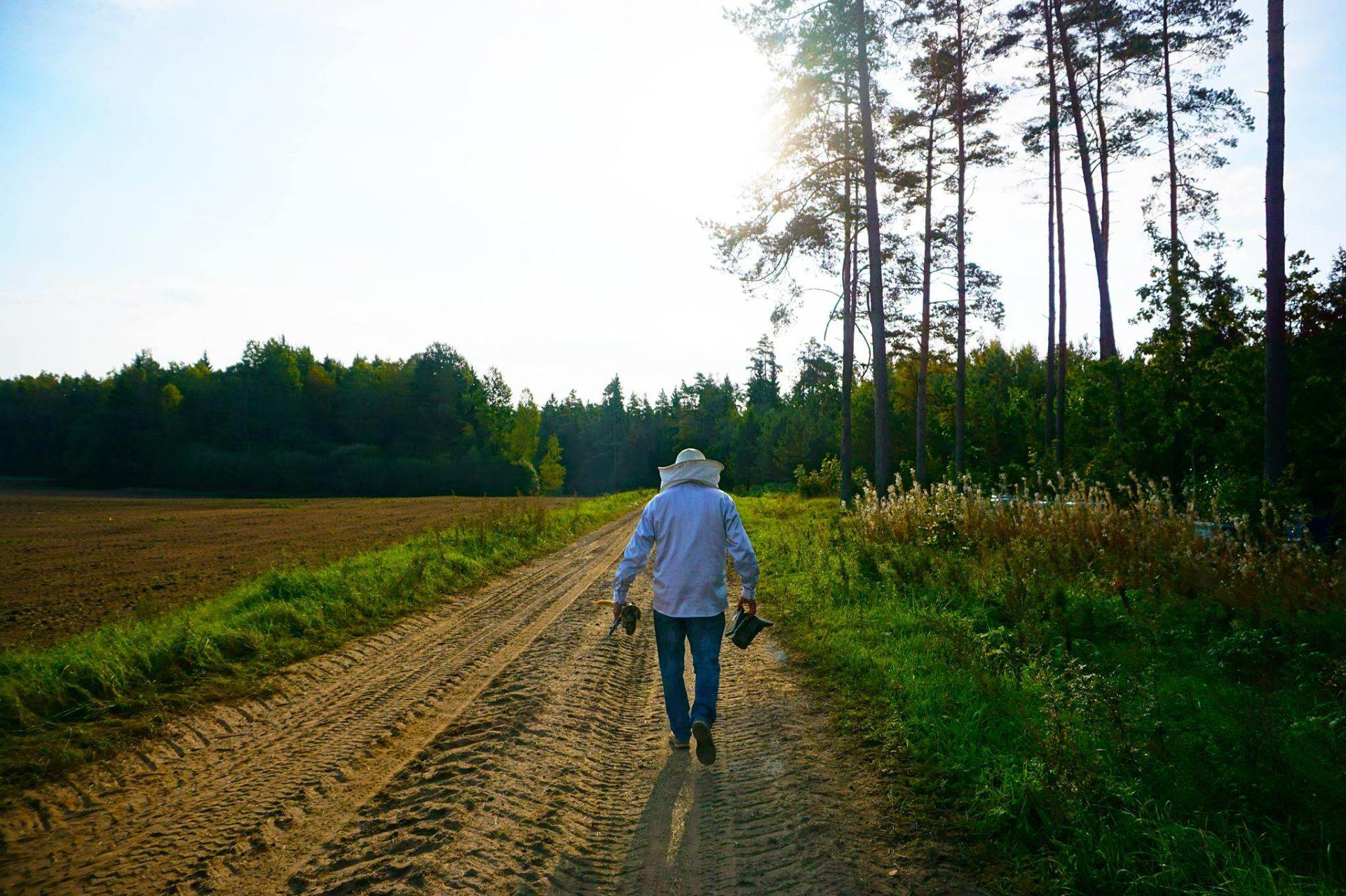 Beekeeper walking on a rural path near Plungė, Lithuania